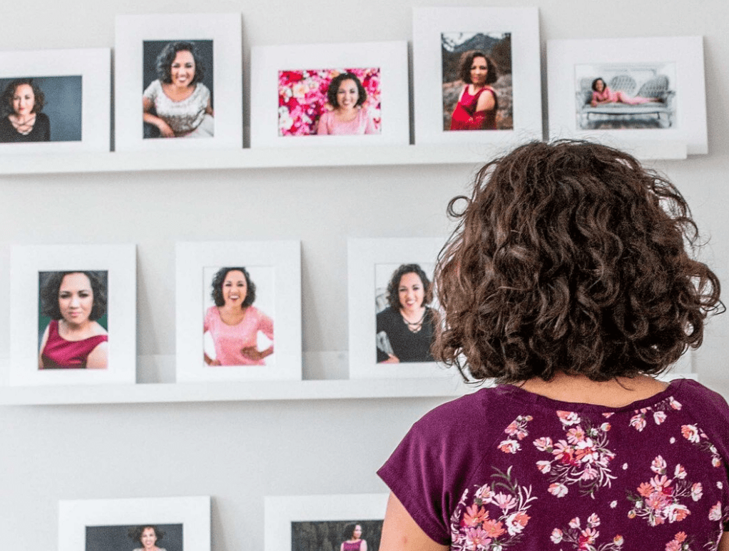 Woman staring at printed photos on wall for Emily Pearl Photography shoot